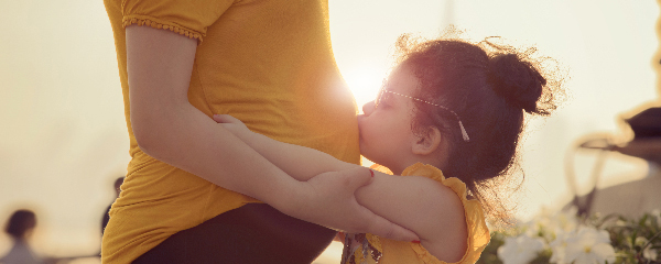 Girl kissing mom's tummy