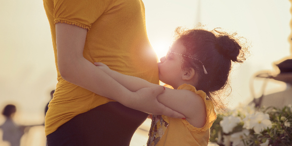 Girl kissing mom's tummy